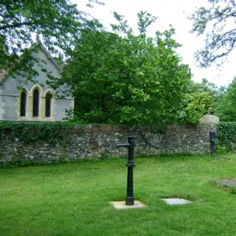 old fashioned water pump out side the church wall